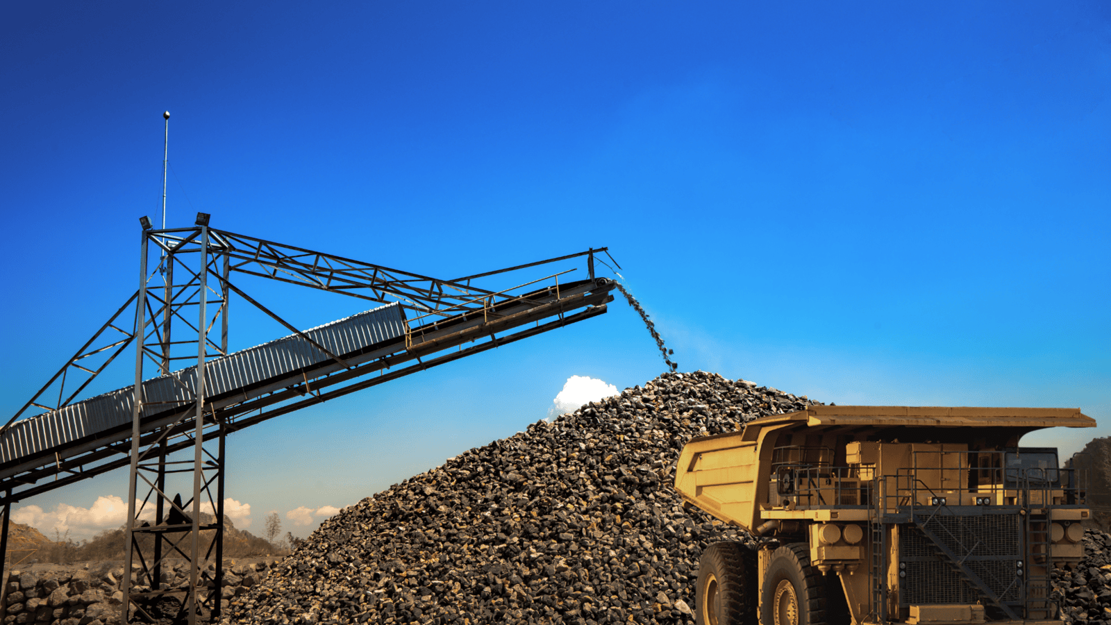 Mining conveyor belt depositing rocks into a truck